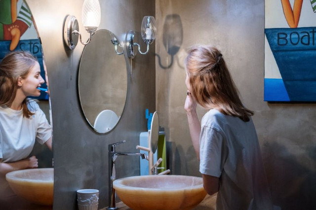 Femme utilisant une brosse à dents Beurer dans sa salle de bain