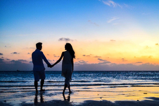 couple marchant sur une plage au coucher de soleil