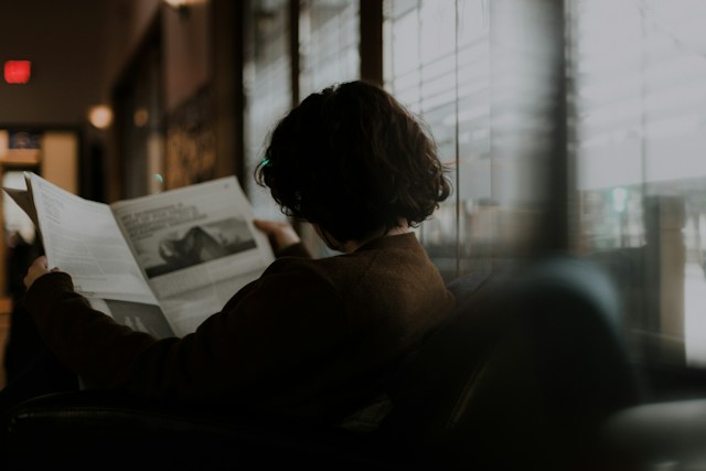 femme lisant le journal L'Express dans un café