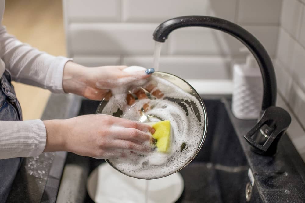 femme faisant la vaisselle avec du produit L'Arbre Vert
