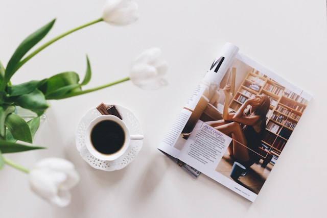 magazine Be posé sur une table blanche, près d'une tasse de café