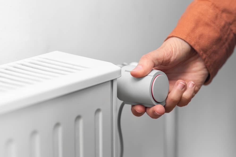 main d'une personne réglant son radiateur fourni par Butagaz