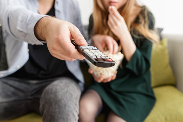 couple regardant la chaîne CNews avec une télécommande à la main