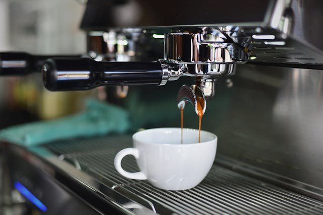 machine à café De Longhi en train de remplir une tasse blanche