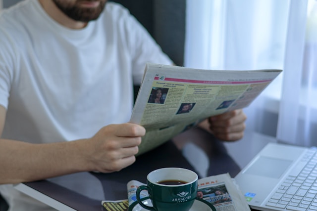 homme lisant le journal DNA en buvant un café