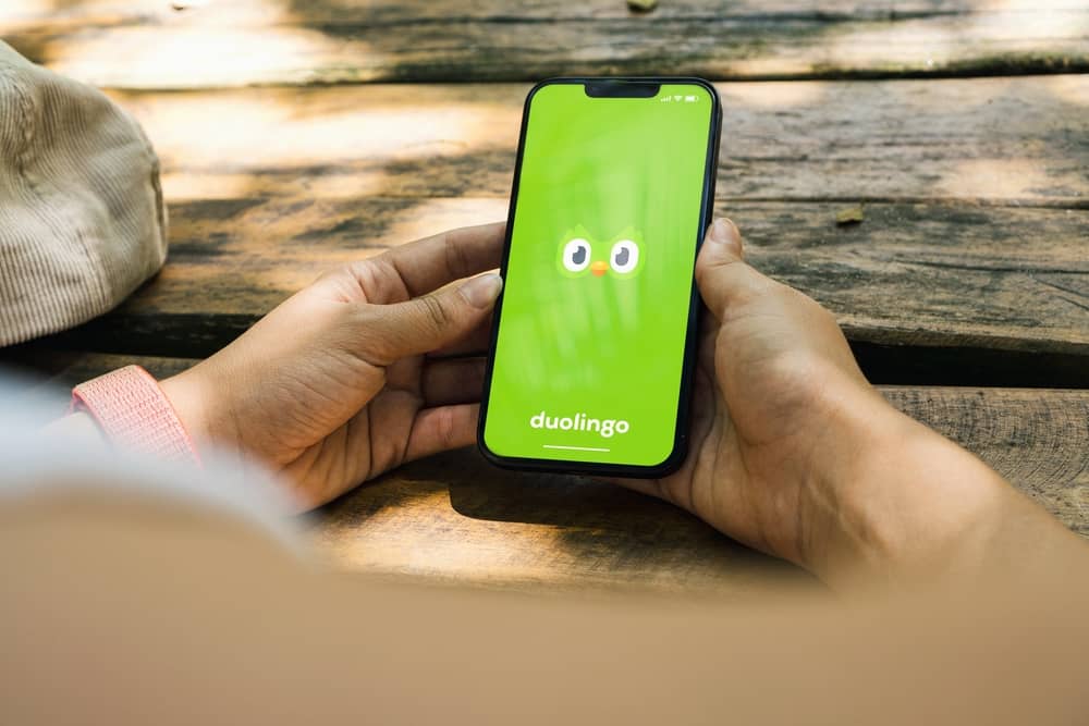 mains d'une personne ouvrant l'application Duolingo sur son smartphone