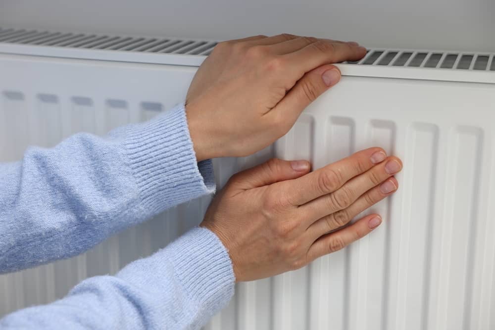mains posées sur un radiateur alimenté par Dyneff Gaz