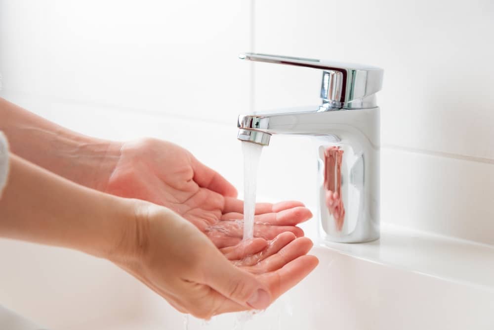 personne se lavant les mains au robinet avec de l'eau d'Eau de Paris