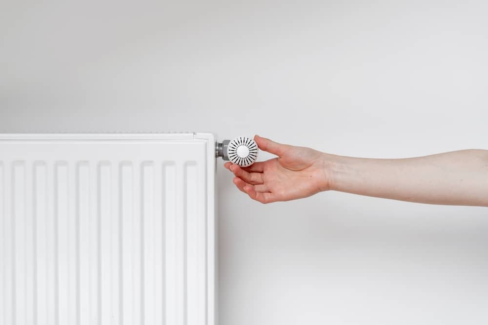 main d'une personne réglant son radiateur fourni par Energies du Santerre