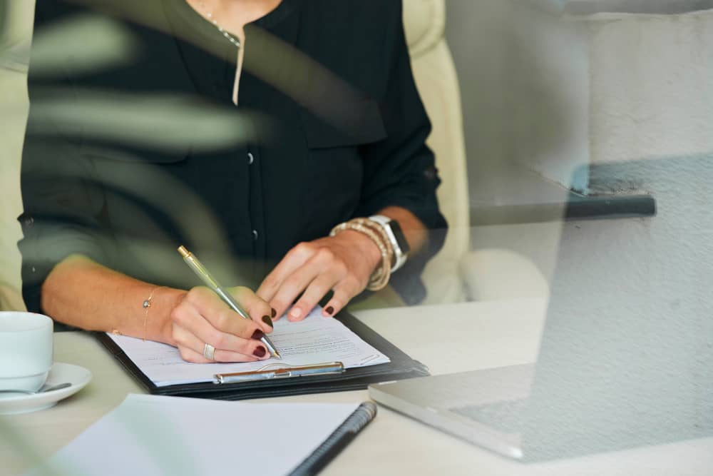 mains d'une femme en train d'écrire une lettre de réclamation pour Filiassur