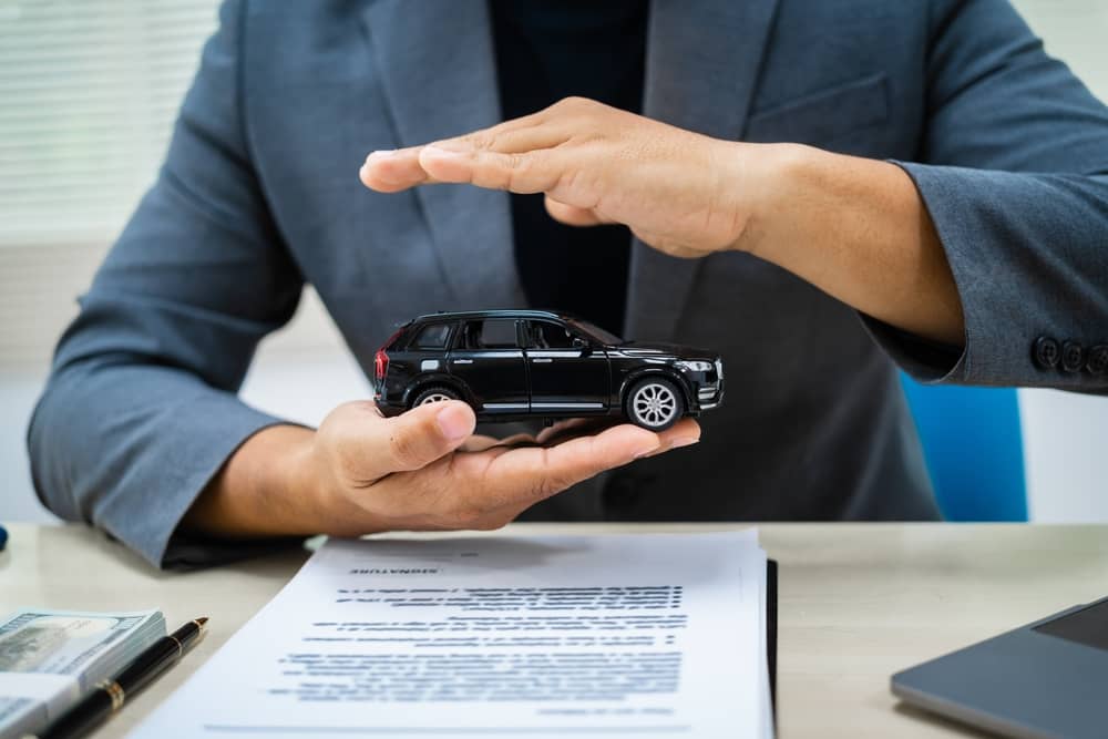 conseiller Generali protégeant une voiture miniature avec ses mains