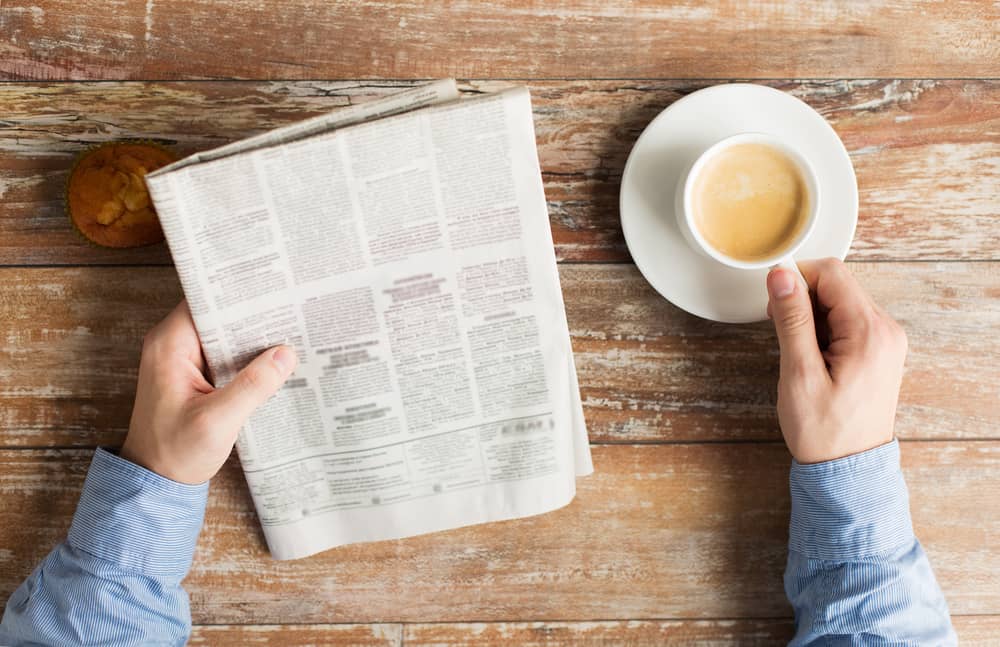 mains d'un homme lisant le journal La Provence avec un café