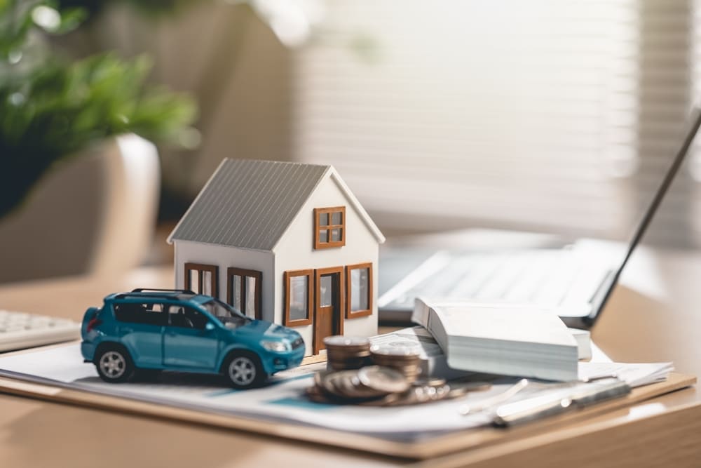 petite maison et petite voiture posées sur des contrats d'assurance de LSA Courtage