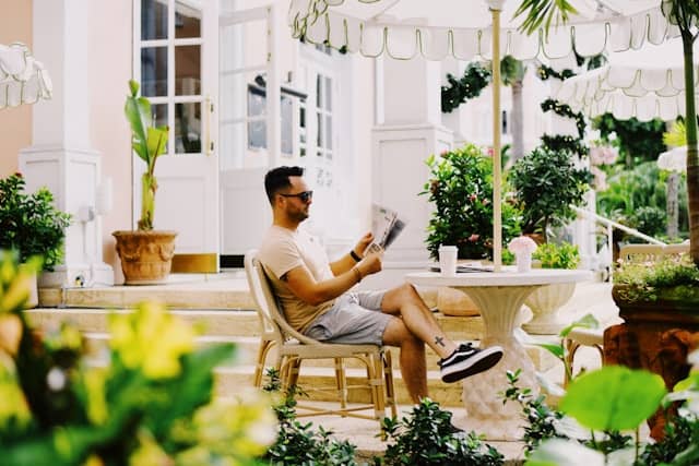 homme lisant un magazine Auto Moto dans son jardin