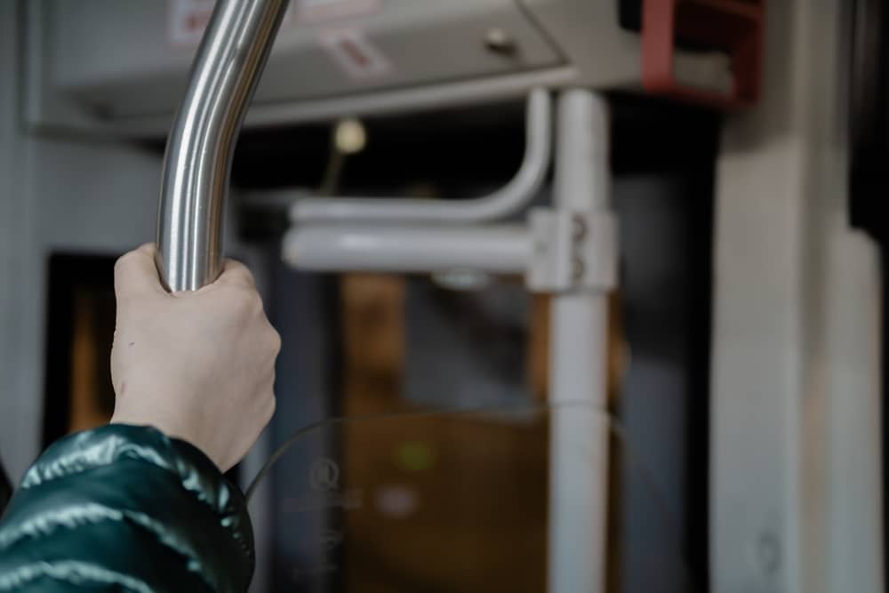 main d'une personne se tenant à une barre dans un bus Naolib