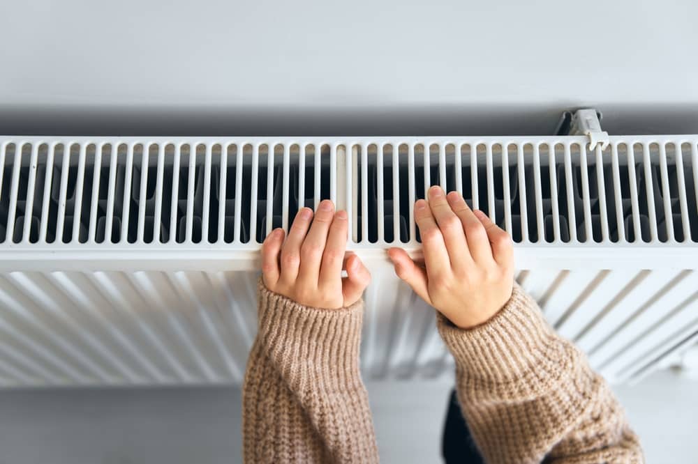 mains d'une femme posées sur un radiateur alimenté par Ohm Energie