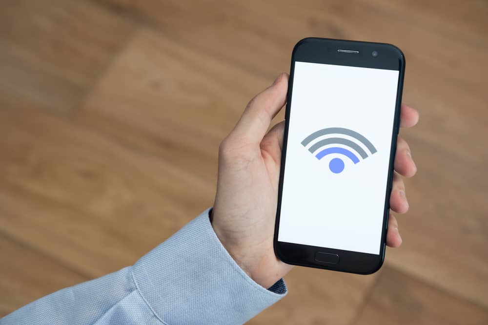 main d'une personne tenant un smartphone avec une connexion Wi-Fi Ozone