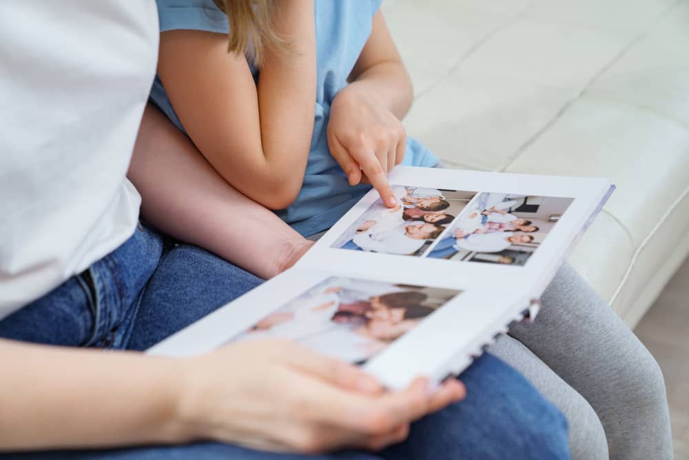 une mère et sa fille regardent un album photo réalisé sur Photoweb