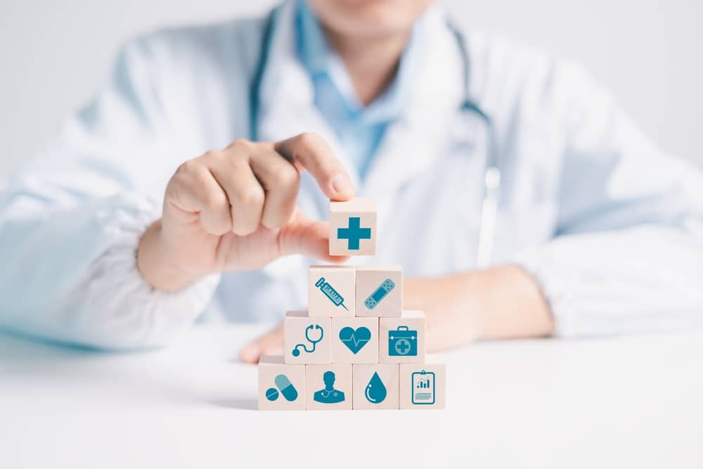 professionnel de santé empilant des blocs en bois avec des logos liés à la santé